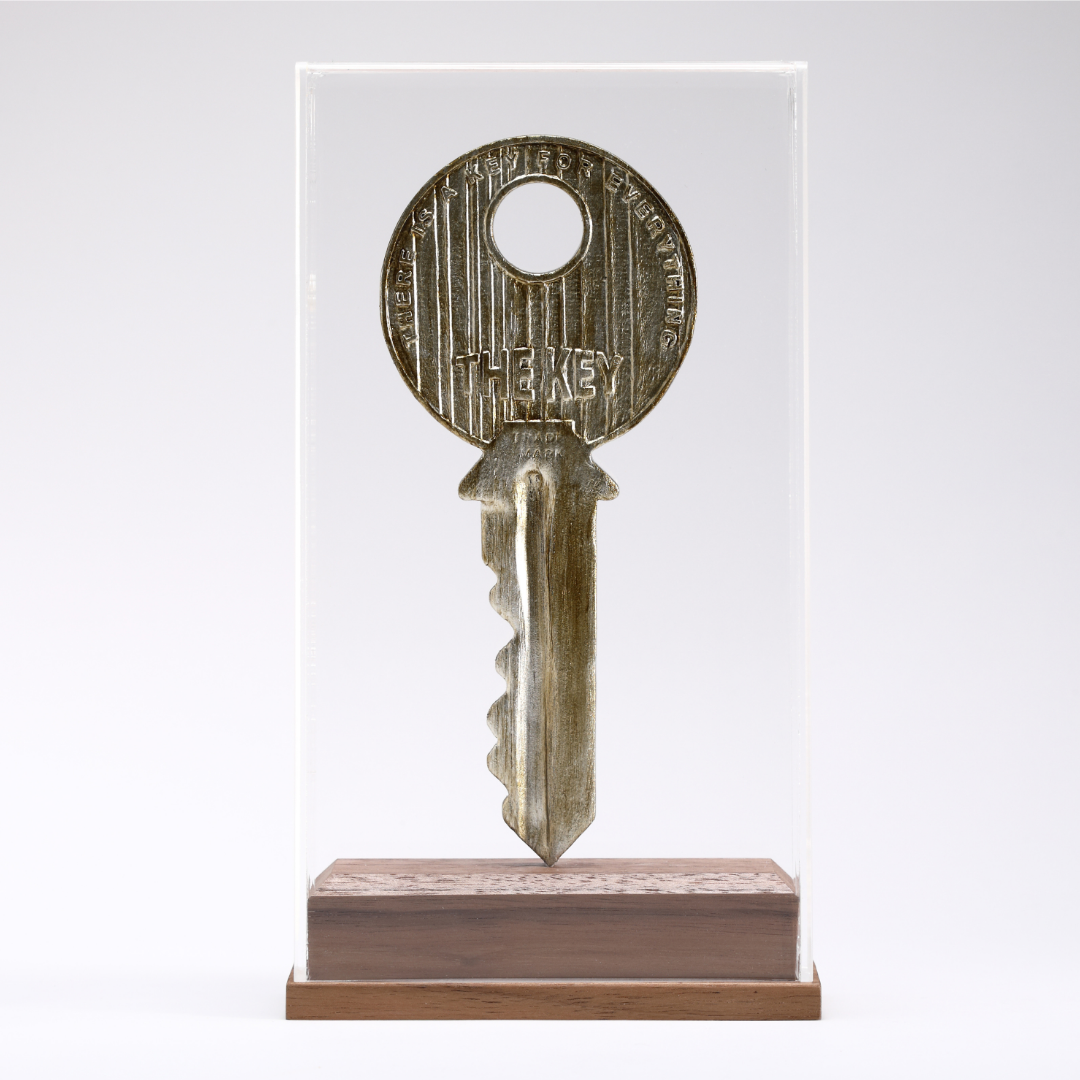 Scultura 'The Key' di Johnny Hermann, rappresentando una chiave in bronzo che eleva il quotidiano a arte.