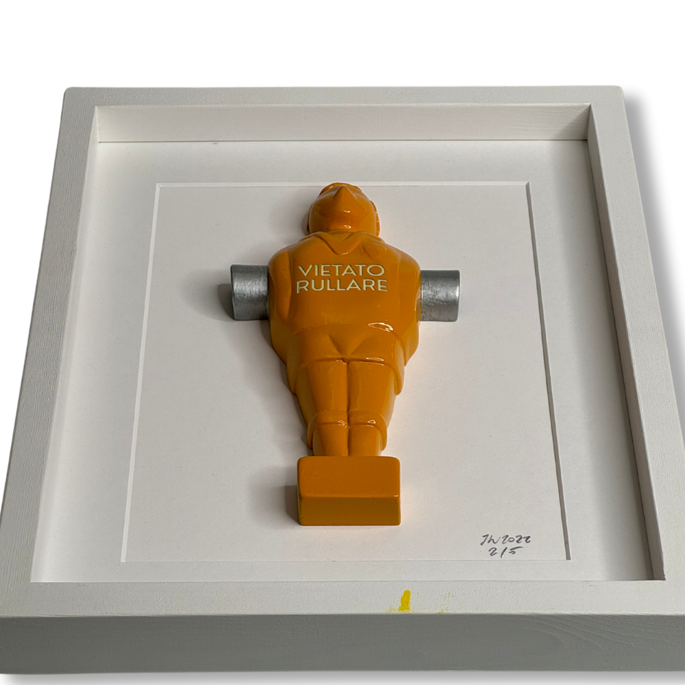 Omino calciobalilla arancione in cornice vista dall'alto