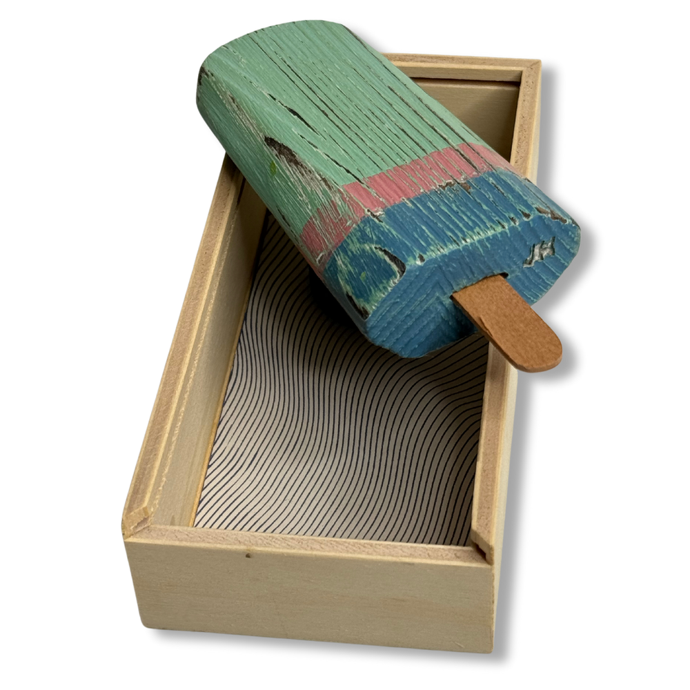 Gelato in legno verde e rosa appoggiato sulla scatola