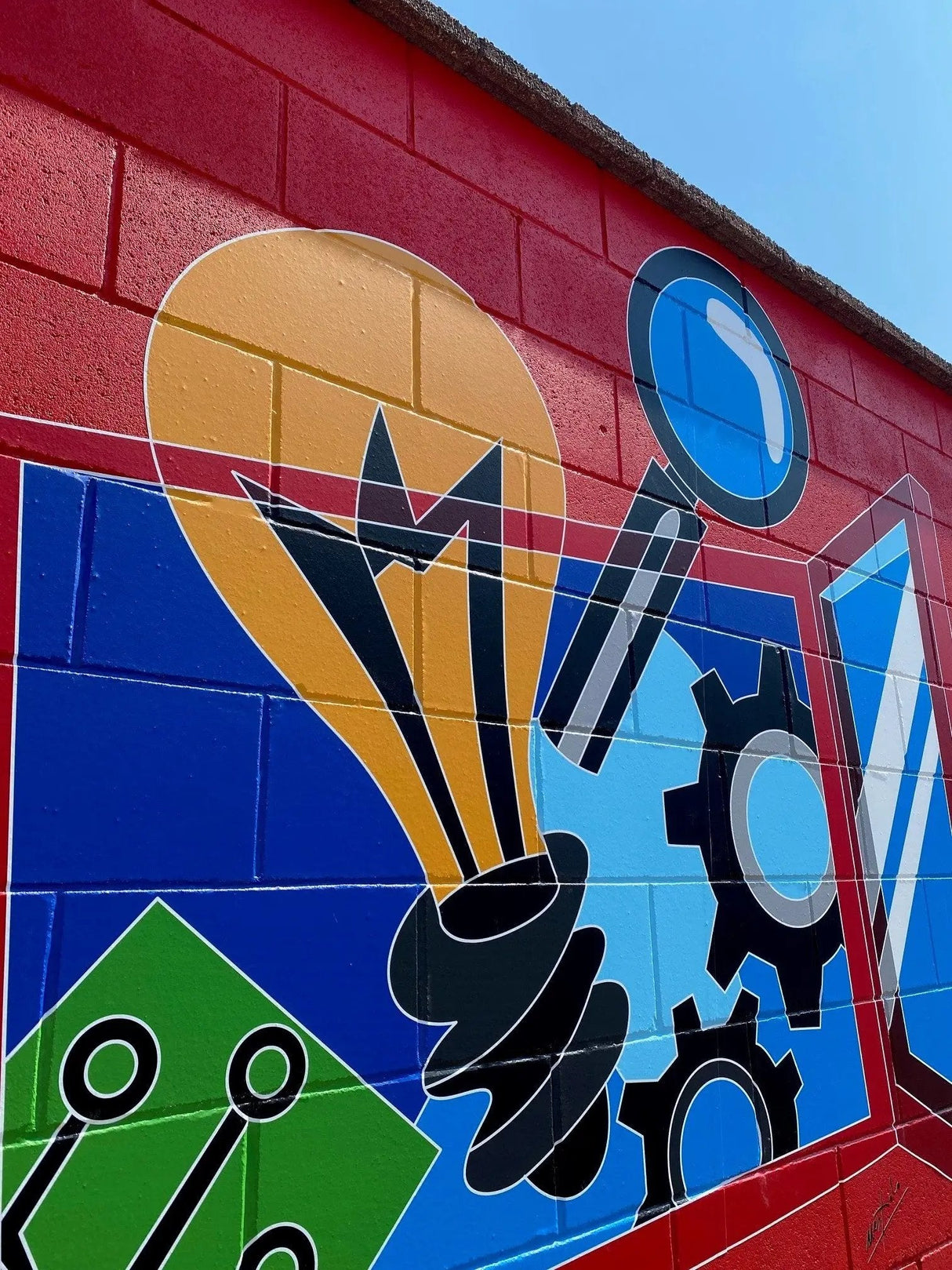 Murale con lampadina e ingranaggi su muro rosso