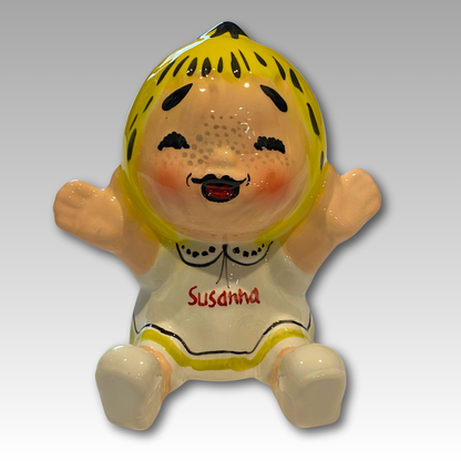 Statuetta in ceramica di 'Susanna Tuttapanna' seduta, con un'espressione felice, ideale per portare gioia in ogni casa.