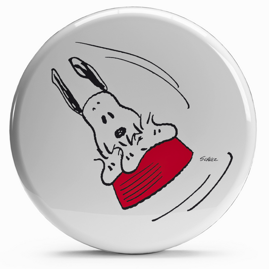 Bollino adesivo di Snoopy che fa un'acrobazia sulla sua ciotola volante rossa, diametro 2,5 cm, per appassionati dei Peanuts.